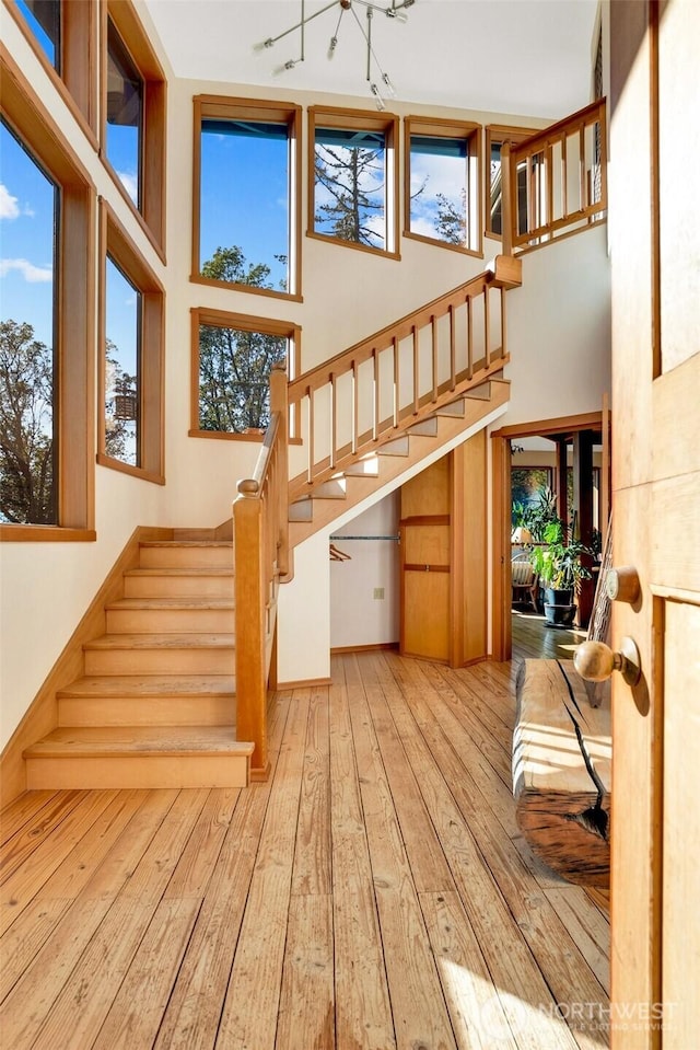 staircase featuring a towering ceiling and hardwood / wood-style flooring