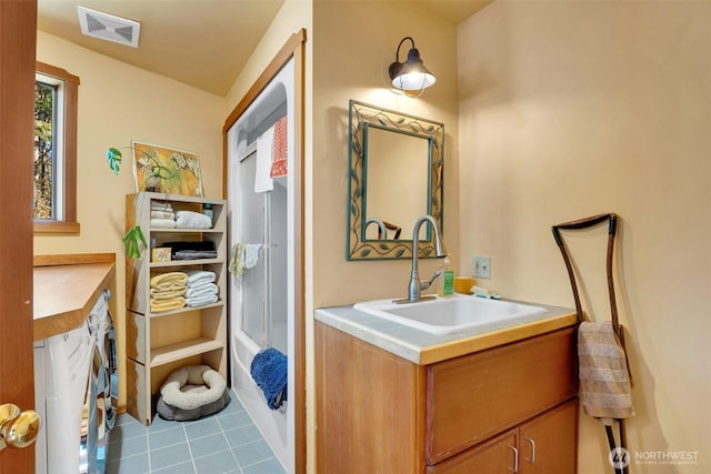 bathroom with vanity, visible vents, washing machine and clothes dryer,  shower combination, and tile patterned flooring