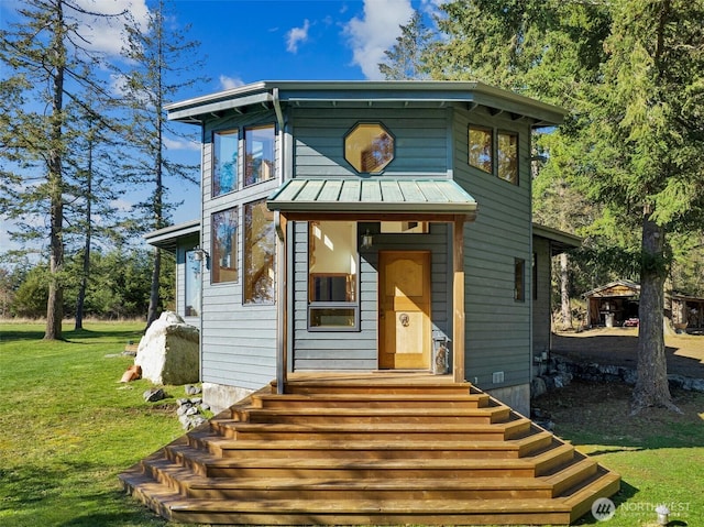 view of front of house featuring entry steps, a front yard, a standing seam roof, and metal roof