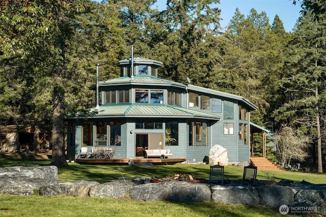 view of front of home featuring a standing seam roof, a wooden deck, metal roof, and a front lawn