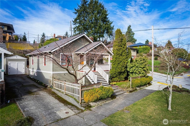 bungalow with a garage, stairway, a storage unit, an outdoor structure, and a front yard