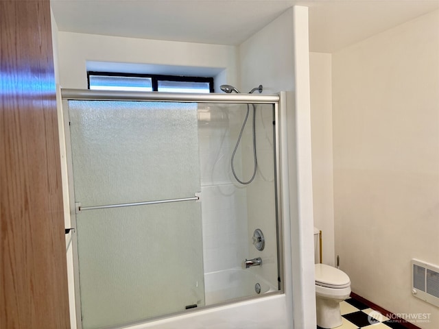 full bath featuring heating unit, combined bath / shower with glass door, and toilet