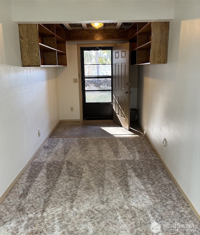 interior space with carpet floors, beamed ceiling, baseboards, and tile patterned floors