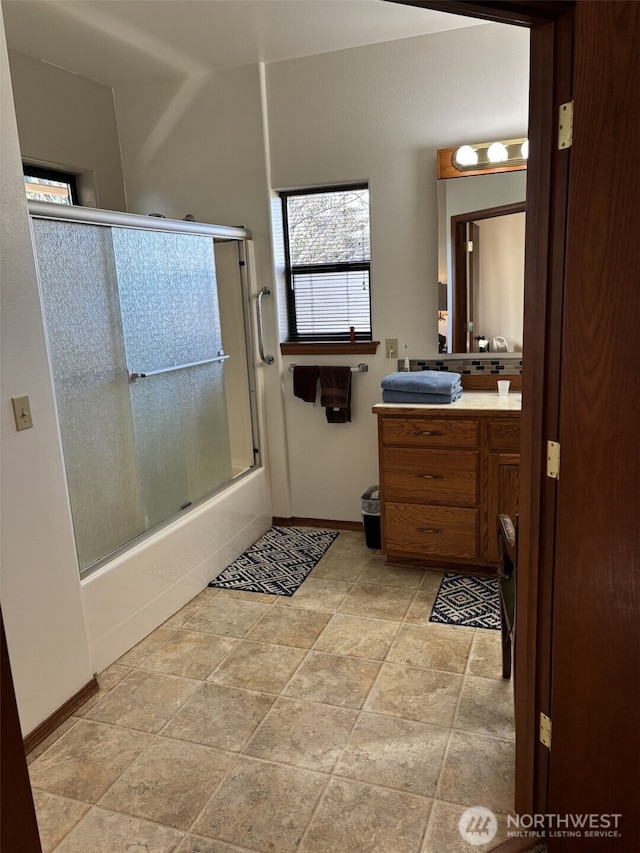 bathroom with baseboards, combined bath / shower with glass door, and vanity