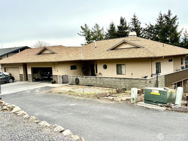 single story home featuring fence, a garage, driveway, and a shingled roof