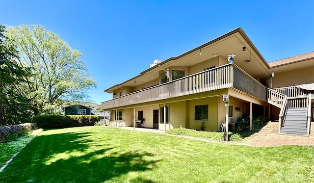 back of property featuring a patio, a wooden deck, a lawn, and stairs