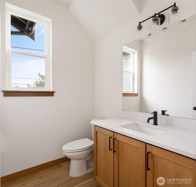 bathroom featuring baseboards, toilet, wood finished floors, vaulted ceiling, and vanity