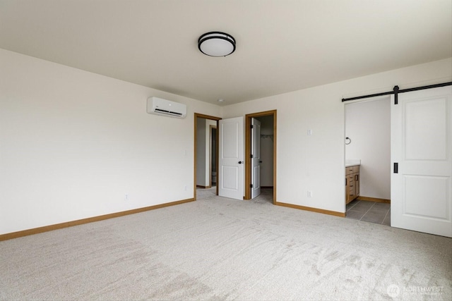 unfurnished bedroom with light colored carpet, a wall unit AC, baseboards, and a barn door