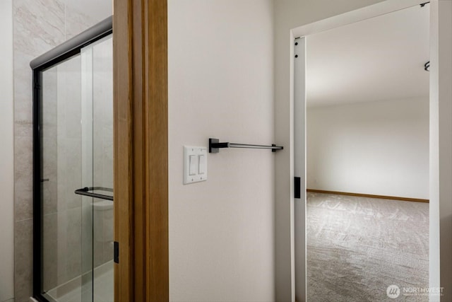 bathroom with a shower stall and baseboards