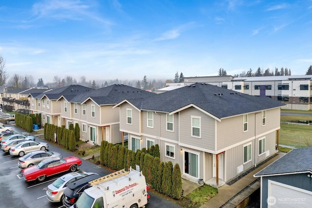 exterior space with uncovered parking, a residential view, and roof with shingles