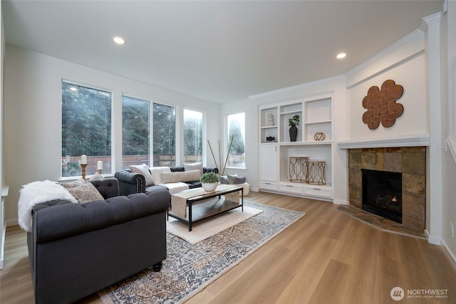 living room with recessed lighting, baseboards, a tiled fireplace, and wood finished floors