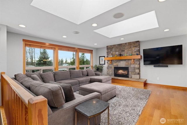 living area with a skylight, a fireplace, wood finished floors, and recessed lighting