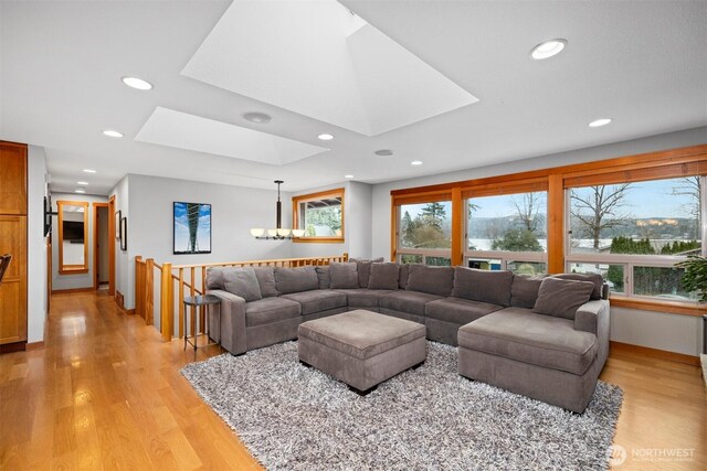 living room with a chandelier, a skylight, light wood finished floors, and recessed lighting