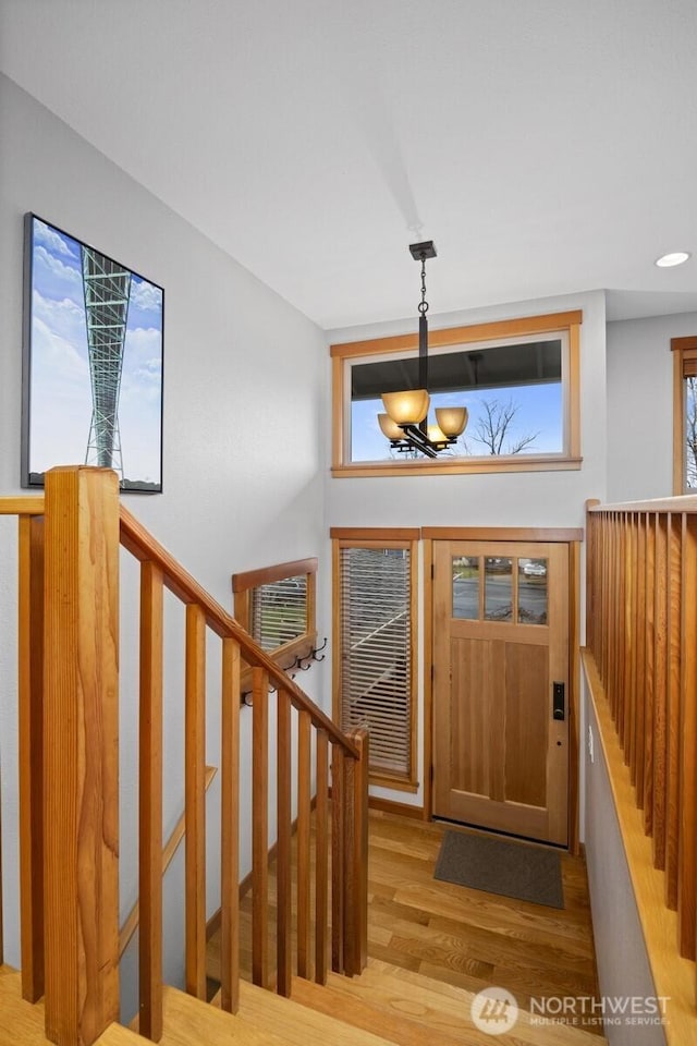 entryway featuring recessed lighting, stairway, an inviting chandelier, and wood finished floors