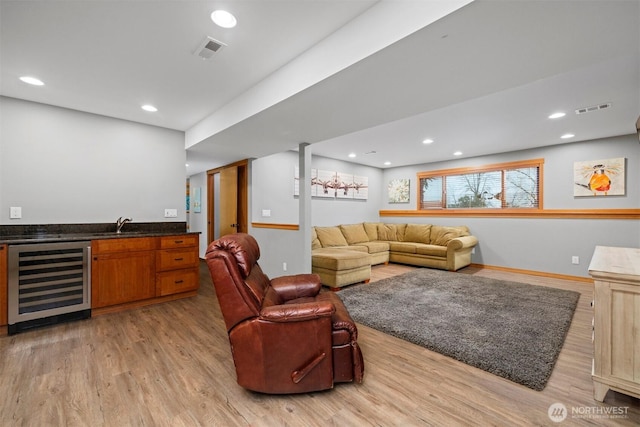 living area with light wood finished floors, wine cooler, indoor wet bar, and visible vents