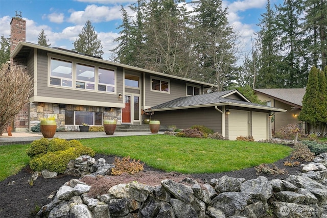 raised ranch with entry steps, stone siding, a chimney, an attached garage, and a front yard