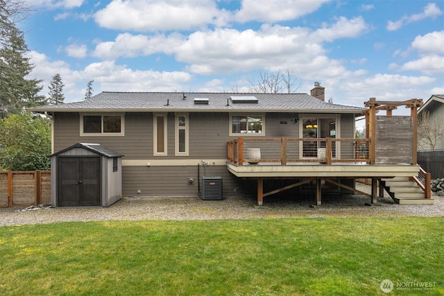 rear view of house featuring a yard, a storage shed, fence, an outdoor structure, and a wooden deck