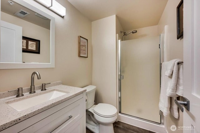 bathroom featuring toilet, wood finished floors, visible vents, vanity, and a shower stall