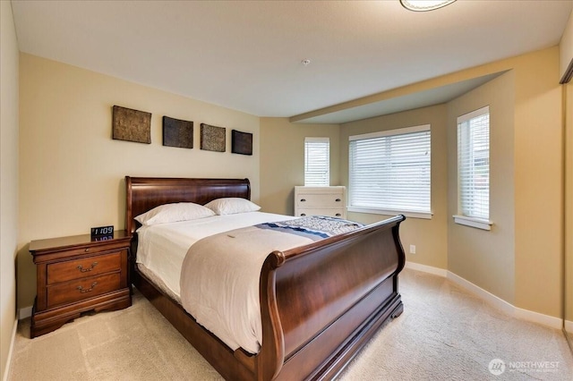 bedroom with light colored carpet and baseboards