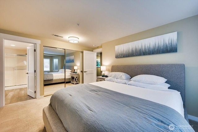 bedroom featuring light colored carpet, a closet, visible vents, and ensuite bathroom