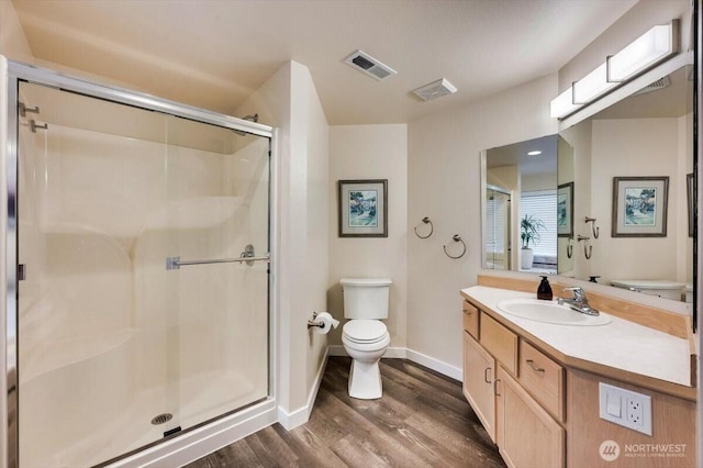 full bathroom featuring toilet, wood finished floors, visible vents, vanity, and a shower stall