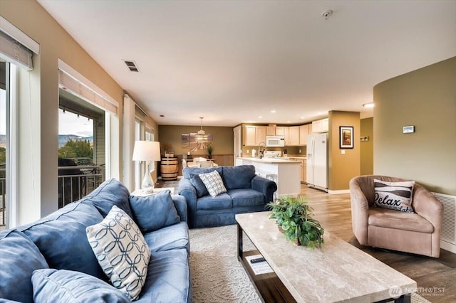 living room with recessed lighting, visible vents, light wood-style flooring, and baseboards