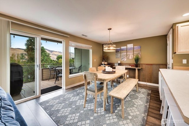 dining space featuring dark wood-type flooring, wainscoting, and visible vents