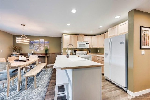 kitchen with white appliances, light wood-style flooring, a breakfast bar area, light countertops, and recessed lighting