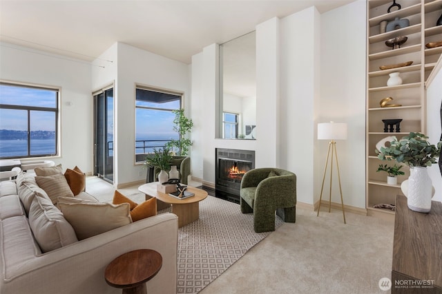 living room with a warm lit fireplace, carpet floors, and baseboards