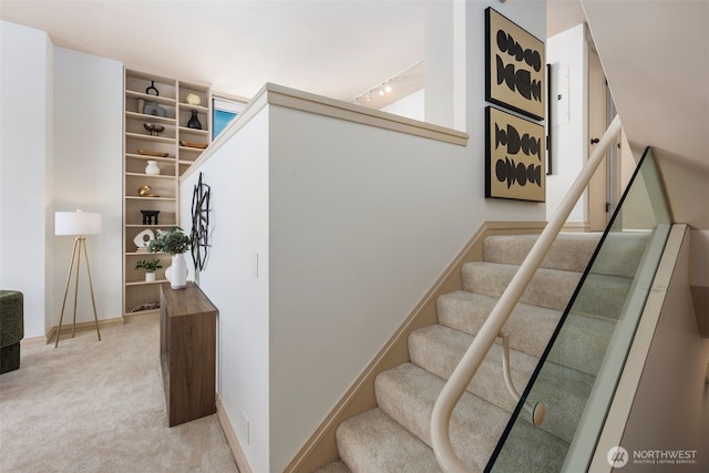 staircase with carpet, rail lighting, and baseboards