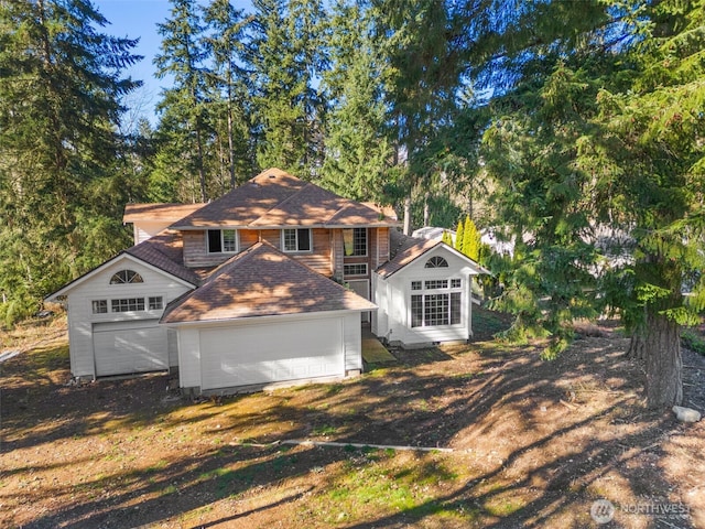 rear view of property featuring driveway and an attached garage