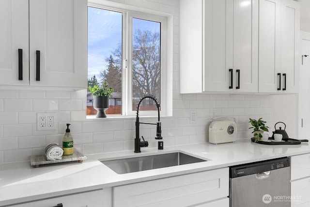 kitchen with stainless steel dishwasher, plenty of natural light, a sink, and white cabinets