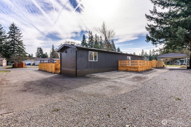 view of side of property with gravel driveway and fence