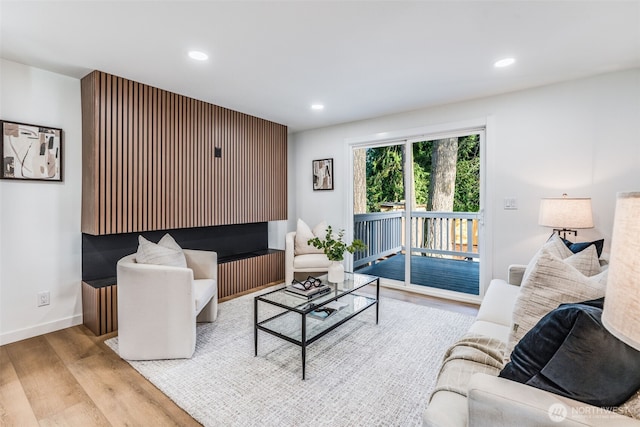 living area with baseboards, wood finished floors, and recessed lighting