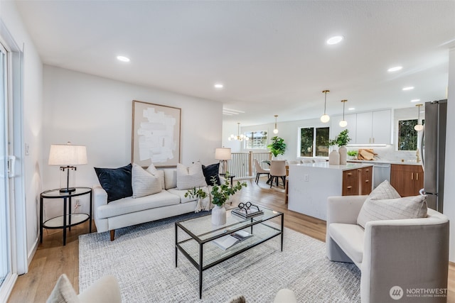 living room featuring a chandelier, light wood-type flooring, and recessed lighting