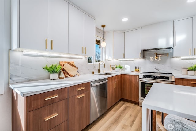 kitchen featuring white cabinets, modern cabinets, appliances with stainless steel finishes, light countertops, and a sink