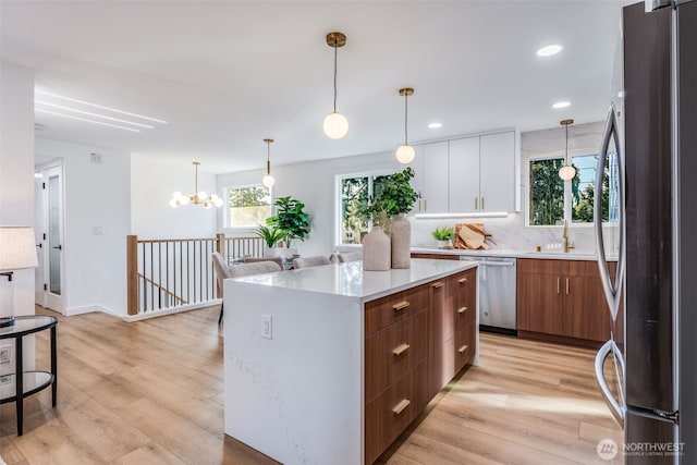 kitchen with stainless steel appliances, light wood-type flooring, modern cabinets, and light countertops