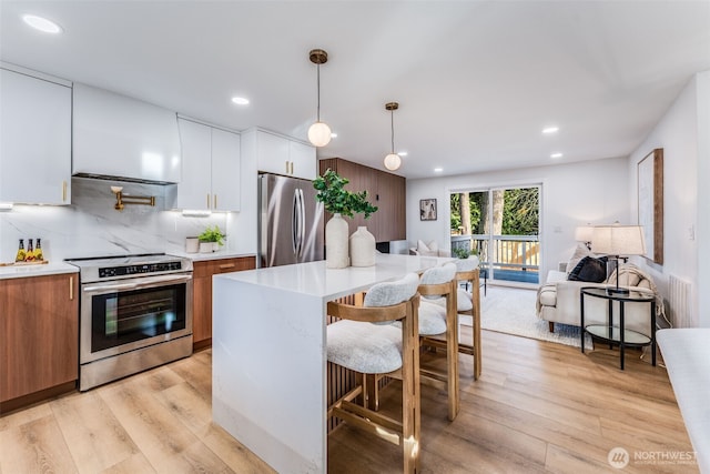 kitchen with open floor plan, light countertops, appliances with stainless steel finishes, light wood finished floors, and modern cabinets