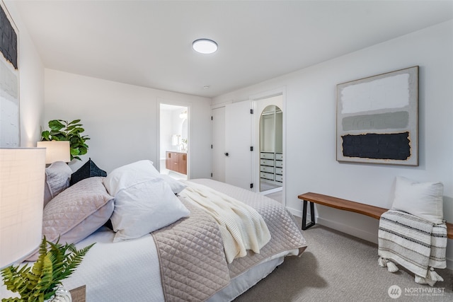 bedroom with carpet floors, arched walkways, baseboards, and ensuite bathroom