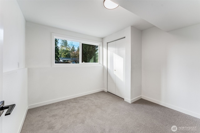 interior space featuring baseboards, a closet, and light colored carpet