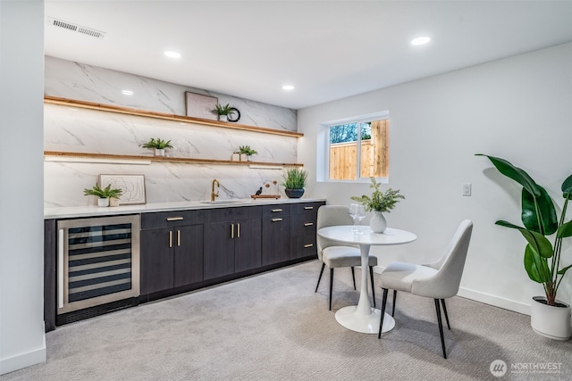 bar featuring light colored carpet, beverage cooler, visible vents, and a sink