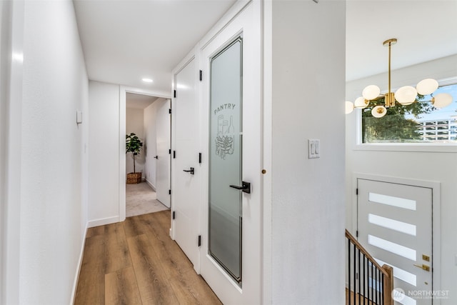 hallway with a notable chandelier and wood finished floors