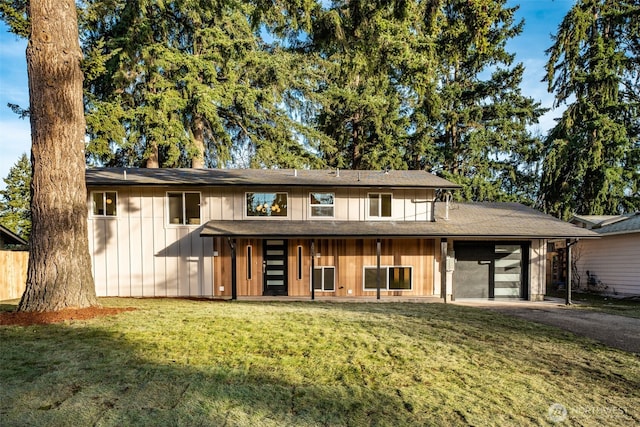 view of front of property featuring aphalt driveway, a front lawn, board and batten siding, and an attached garage