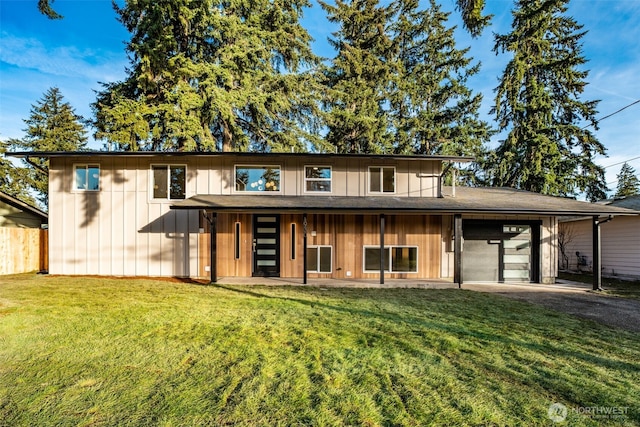 view of front of house featuring a garage, fence, driveway, a front lawn, and board and batten siding