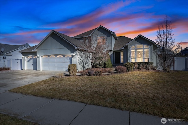 traditional home featuring a garage, driveway, fence, and a front yard