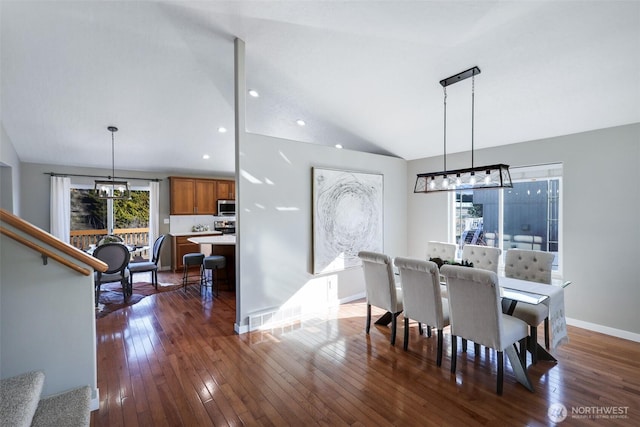 dining space with vaulted ceiling, dark wood-type flooring, a chandelier, and baseboards