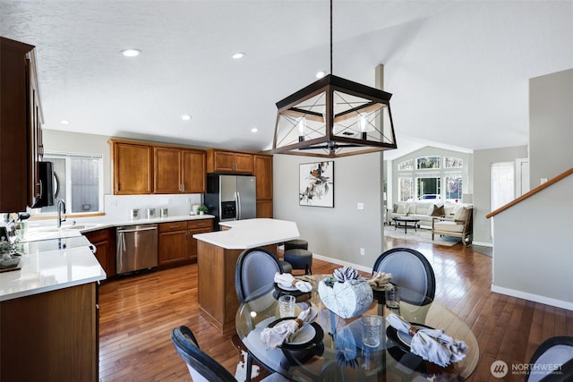 kitchen featuring lofted ceiling, appliances with stainless steel finishes, light countertops, and a center island