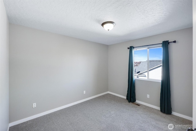 spare room featuring visible vents, a textured ceiling, baseboards, and carpet flooring