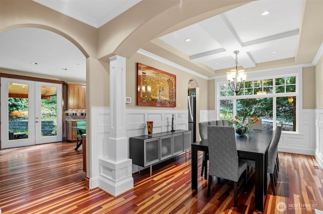 dining room featuring wainscoting, coffered ceiling, wood finished floors, and a healthy amount of sunlight