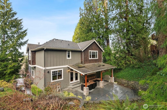 back of property with entry steps, roof with shingles, and a patio